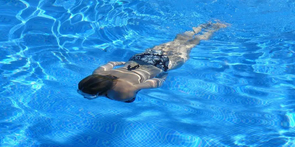 donna nuota sotto l'acqua in piscina