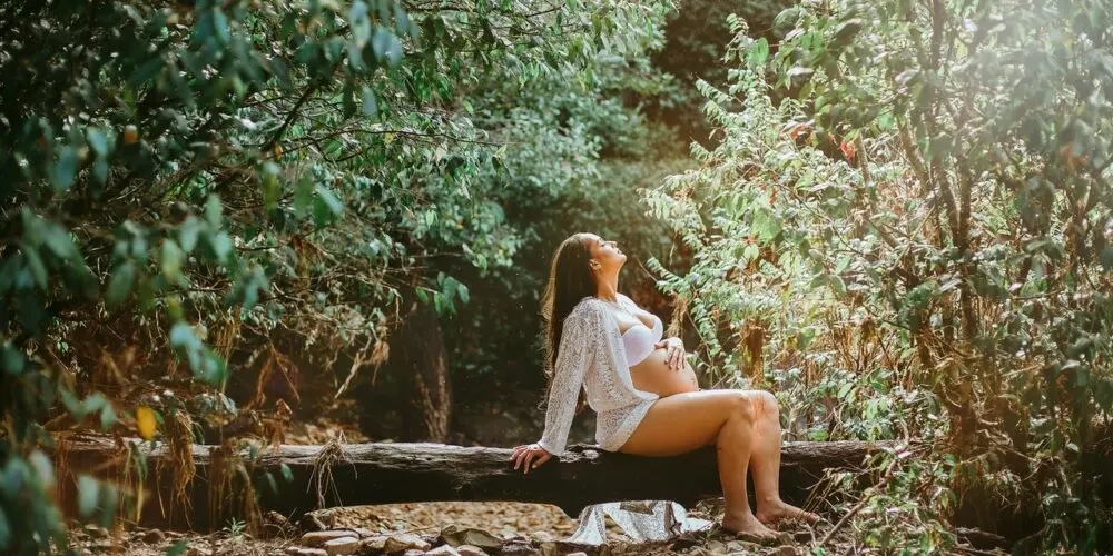 Ragazza incinta seduta su un tronco