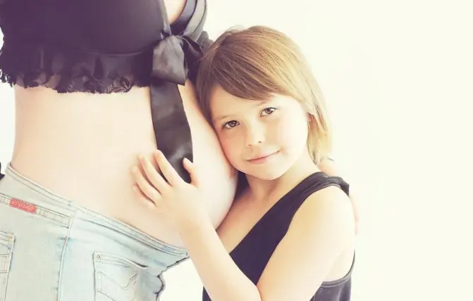bambina abbraccia la pancia della mamma in gravidanza