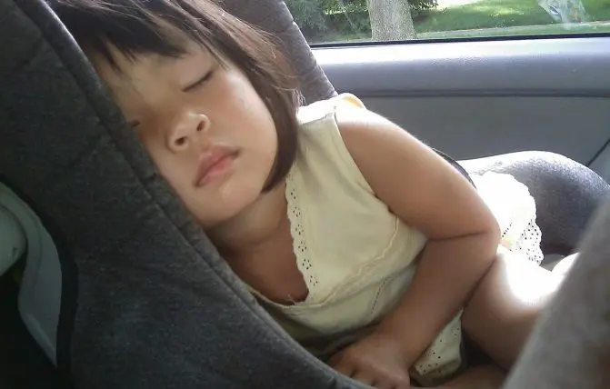 bambina asiatica dorme coricata nel seggiolino auto