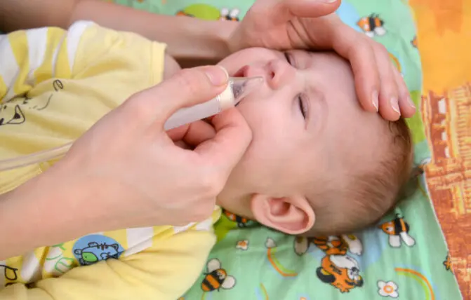 mamma libera il naso chiuso del neonato con aspiratore nasale