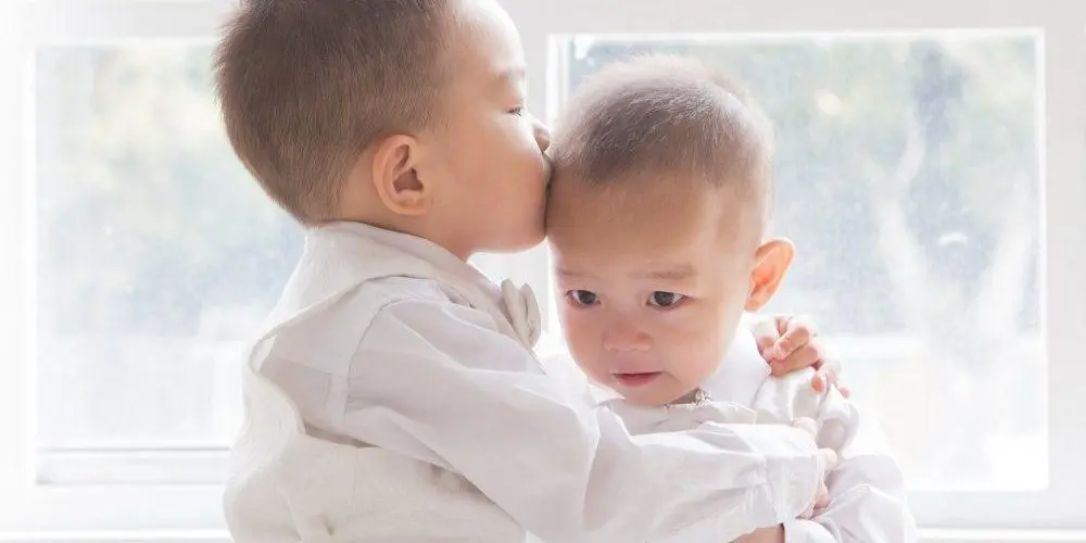 bambino abbraccia e bacia il suo fratellino