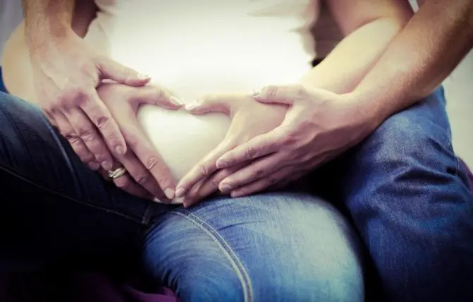 coppia si abbraccia toccando il pancione della donna