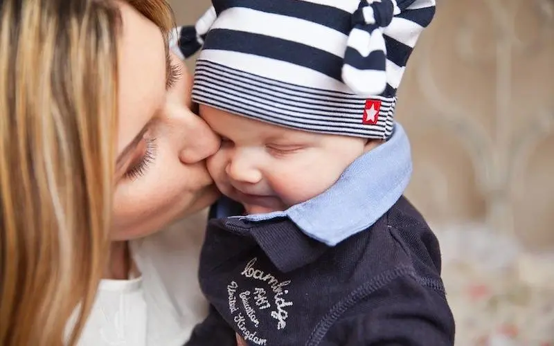 mamma bacia il neonato con cappello in testa