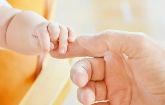 neonato afferra il dito del papà