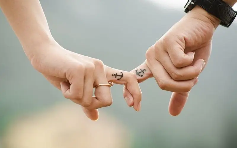dita intrecciate di una coppia con lo stesso tatuaggio