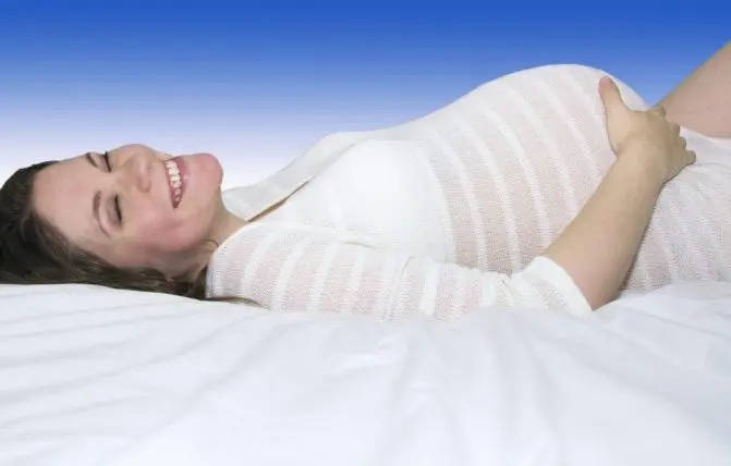 donna incinta coricata di schiena che sorride