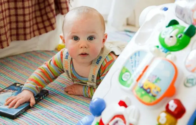 bambino disteso sulla pancia gioca con giocattoli per la prima infanzia