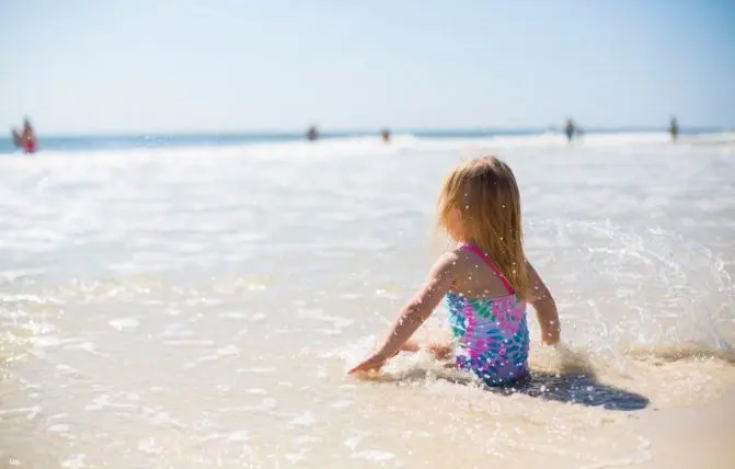 bambina gioca con l acqua in riva al mare