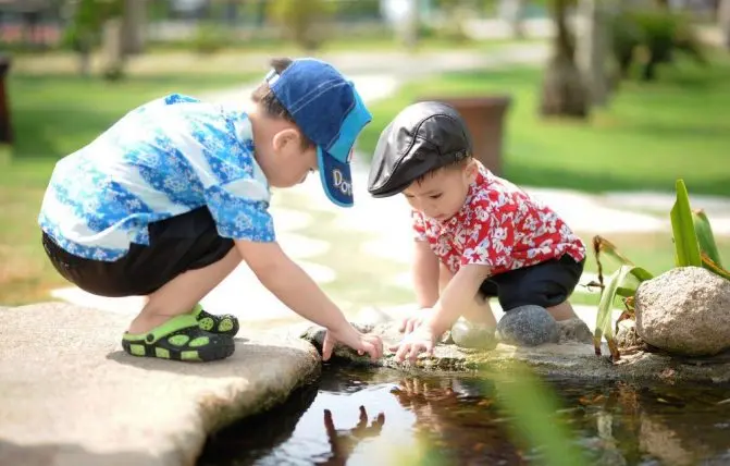 bambini con camicie hawaiane e cappellini giocano nello stagno