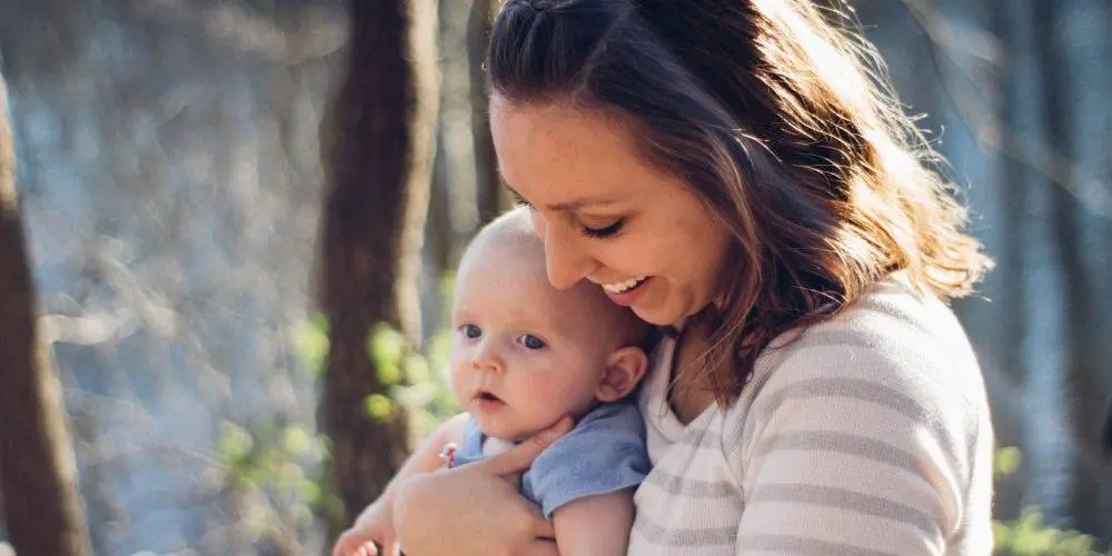 mamma sorride con il braccio il proprio bambino