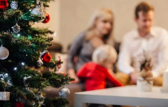 famiglia seduta sul divano vicino ad albero di natale