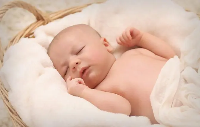 neonato dorme tranquillo dentro la culla avvolto da un lenzuolo bianco