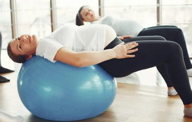 donne in gravidanza fanno esercizio fisico con una palla da fitness blu