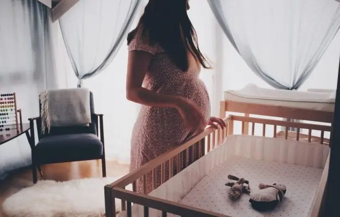 donna incinta vicino al lettino