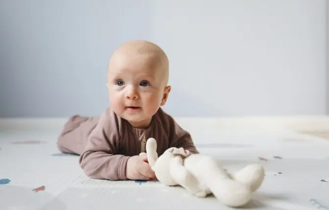 Bambino con peluche fa tummy time