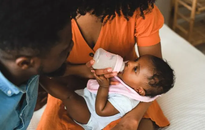 Coppia che dà il biberon a un bambino